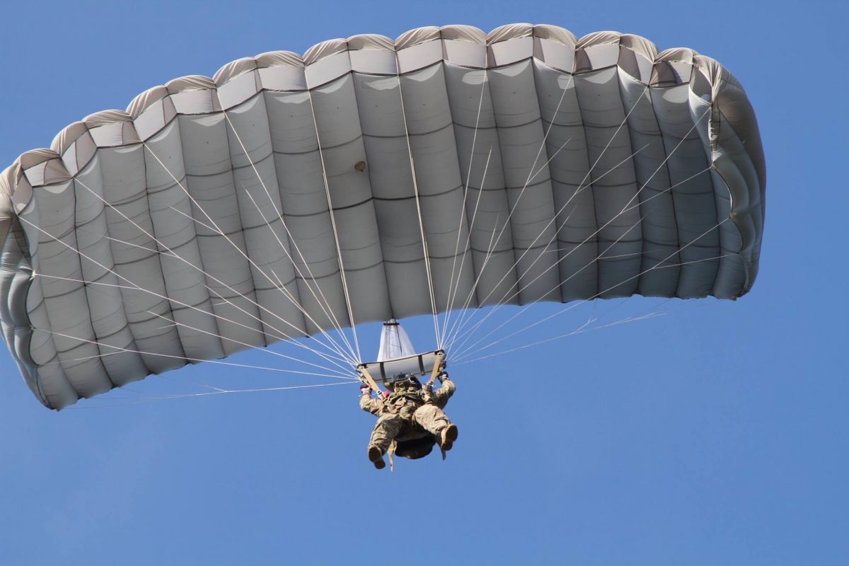 Airborne Systems - Intruder RA-1 Army Ram Air Parachute system for military special forces and beginner jumpers. Carries 450 lbs. Max deployment altitude 25,000 ft. Jumper from below with blue sky. Fort Bragg.
