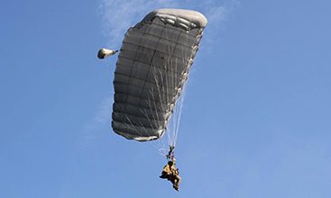 Airborne Systems Intruder RA-1 Army Ram Air Parachute system for military special forces and beginner jumpers. Carries 450 lbs. Max deployment altitude 25,000 ft. Canopy and blue sky.