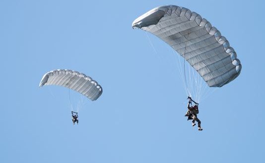 Airborne Systems - Intruder RA-1 Army Ram Air Parachute system for military special forces and beginner jumpers. Carries 450 lbs. Max deployment altitude 25,000 ft. 2 jumpers open canopies, blue sky.
