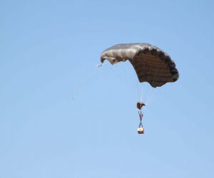 Airborne Systems FC Mini Army cargo delivery parachute system. JPADS / GPADS: Guided Precision Aerial Delivery System. Carries 200-500 lbs. Max deployment altitude 24,500 ft. Canopy and cargo with blue sky.