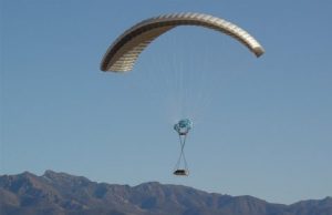Airborne Systems - DragonFly Army Cargo Delivery Parachute System. JPADS 10K System of Choice. Eliptical canopy carries loads up to 10,000 lbs. Max altitude 24,500 ft. Military cargo and canopy, blue sky and mountains.