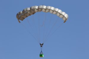 Airborne Systems - FC Mini Army cargo delivery parachute system. JPADS / GPADS: Guided Precision Aerial Delivery System. Carries 200-500 lbs. Max deployment altitude 24,500 ft. Military Cargo and inflated canopy, blue sky.