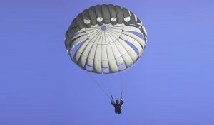 Airborne Systems MC-6 Army Troop Parachute non-steerable for military jumpers. Low opening. Carries up to 400 lbs. Minimum deployment altitude 500 ft. Static line parachute free fall military jumper open canopy. From below with blue almost purple sky.