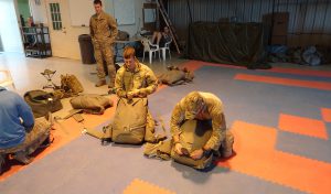 Airborne Systems T-11, MC-6. Military troop parachute training. Reserve non-steerable parachute systems for riggers & jumpers. Free fall skills & combo drop army missions training. Riggers repacking parachutes in training facility. 3 military jumpers prep.