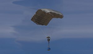 Airborne Systems FireFly Army Cargo Delivery Parachute System. JPADS 2K System of Choice. Carries unmanned loads up to 2,200 lbs. Max deployment altitude 24,500 ft. Deployed canopy with blue cargo unit, blue skies and whispy clouds.