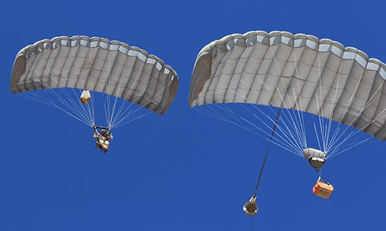 Airborne Systems Combo Drop MicroFly II Army Cargo delivery system. JPADS / GPADS: Guided Precision Aerial Delivery System. Use with any Airborne Systems Ram Air Canopy. Troop jumper and cargo parachutes from below with blue sky.