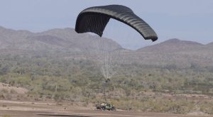 Airborne Systems DragonFly Army Cargo Delivery Parachute System landing with army vehicle payload. JPADS 10K System of Choice. Eliptical canopy carries loads up to 10,000 lbs. Max altitude 24,500 ft.