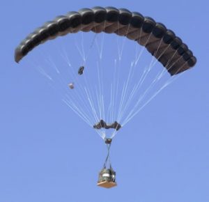 Airborne Systems FireFly Army Cargo Delivery Parachute System. JPADS 2K System of Choice. Carries unmanned loads up to 2,200 lbs. Max deployment altitude 24,500 ft. Deployed canopy with cargo on platform and blue sky.
