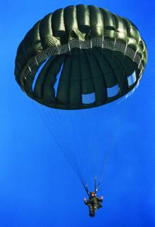 Airborne Systems MC-6 Army Troop Parachute non-steerable for military jumpers. Low opening. Carries up to 400 lbs. Minimum deployment altitude 500 ft. Lone soldier with blue sky and green chute.