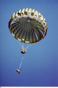 Airborne Systems. MC-6 Army Troop Parachute non-steerable for military jumpers. Low opening. Carries up to 400 lbs. Minimum deployment altitude 500 ft. Deployed canopy and cargo with blue sky