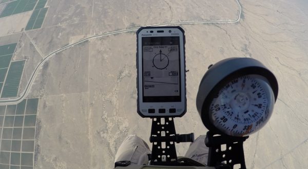 Airborne Systems jTrax Navaid parachute navigation system for army and military jumpers and JPADS and GPADS cargo guided precision aerial delivery systems. Close up of apparatus and compass pre-jump at 5,000 feet with land in background.