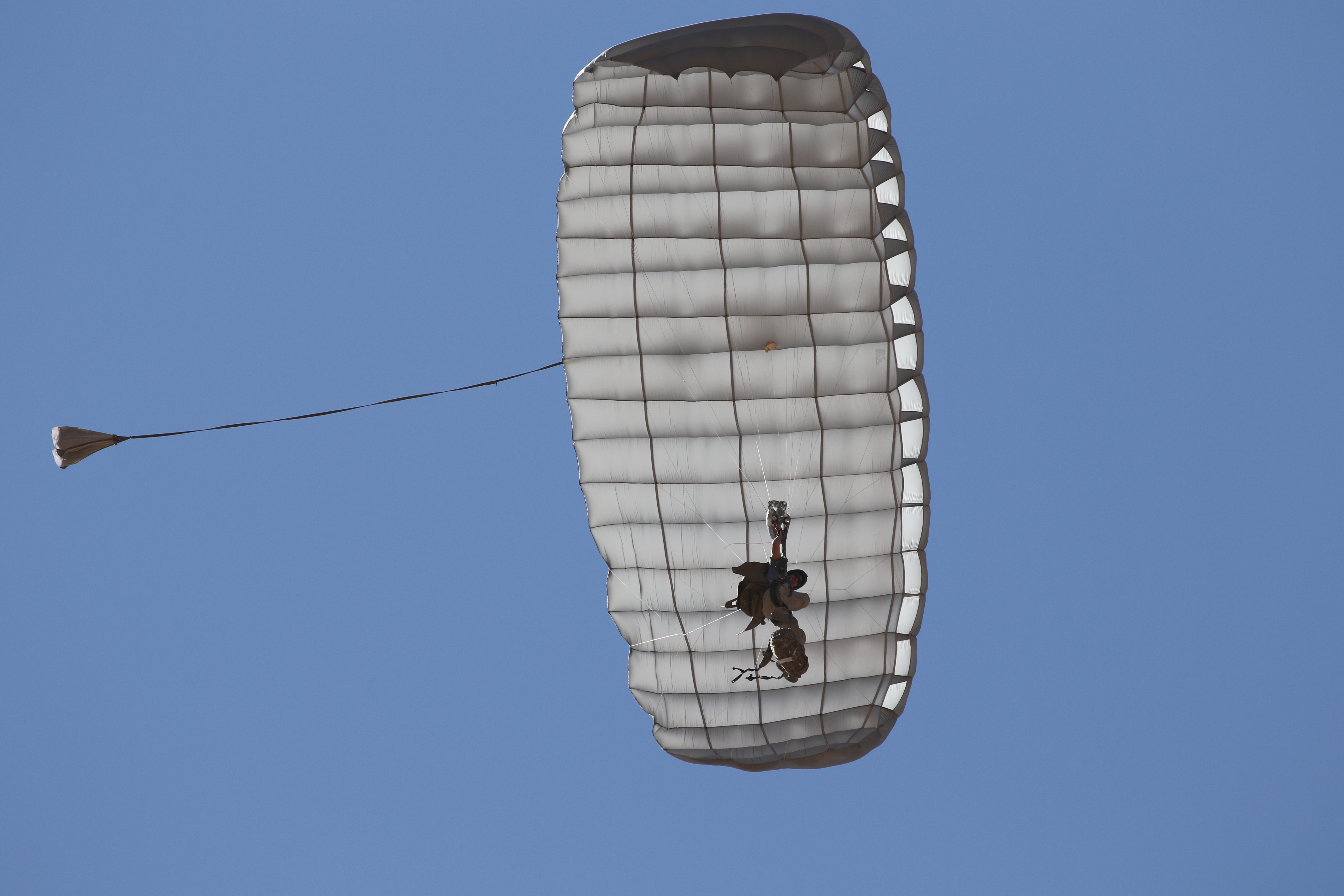 Airborne Systems Hi-5 Army Ram Air Parachute Personnel product system for military special forces jumpers with glide modulation. Carries 485 lbs. Max deployment altitude 25,000 feet. Deployed canopy and parachutist from below with blue sky.